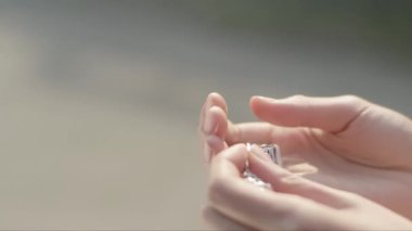 İki elinde de beyaz arka planda mavi çiçekli bir bilezik var. Bir kadının elinin yakın plan görüntüsü.