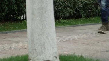 Kot pantolonlu bir adam kaldırımda yürüyor, adamın bacaklarını yakın plan çekiyor.