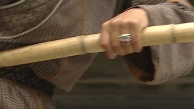 Qing Hanedanlığı kıyafetleri giyen bir adam bambu sırığıyla egzersiz yapıyor.