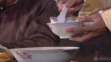 Kaseye birkaç kaşık soya sütü dökülüyor, Qing Hanedanlığı kostümleri ve kızarmış hamur çubukları da arka planda.