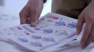 Giysi tasarımı el yazmasını düzenlemek ve kontrol etmek, adamın el hareketlerini yakından incelemek.