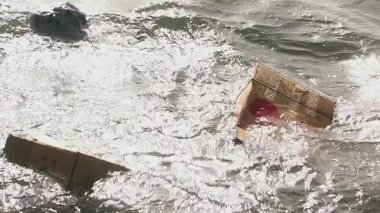 Nehir suyunda yüzen karton kutular ve dokuma çantalar.