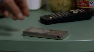 Masadaki eski moda cep telefonunu al ve adamın el hareketlerinin yakın çekim görüntülerini kontrol et.