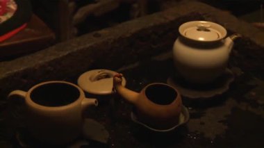 Çeşitli çaydanlıklar ve çay kaseleri masanın üzerinde.