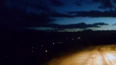Akşamki dağ yolu engebeli araba pencerelerinin perspektifinden görülüyor.