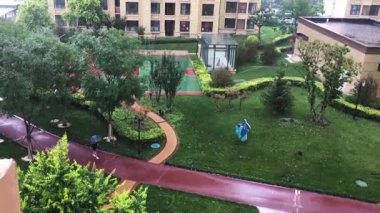 Yağmurda topluluğun yol ve yeşil alanları sabit kamerayla çekiliyor.