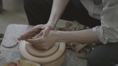 Bir çaydanlık yapıyor, el hareketlerini yakından çekiyor.