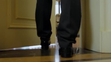 Kapıyı açar, odaya girer, adamın bacaklarını ve ayaklarını kapatır. 