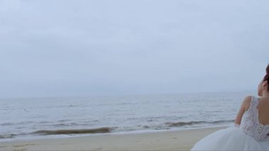 Deniz kenarında oturan gelinlikli yeni evli bir çift.