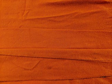 Yatay kıvrımları ve sıcak dokusu ve ince kıvrımları ile kırmızı kumaşın yakın plan çekimi, onu arka plan, tasarım elemanları veya tekstil içeriği için uygun hale getirir..