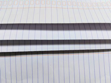 Gölge desenleri ve boyut oluşturan kıvrımları olan bir yığın kağıdın yakın plan fotoğrafı. Kağıttaki mavi ve kırmızı çizgiler ilginç bir geometrik desen elementi ekler.