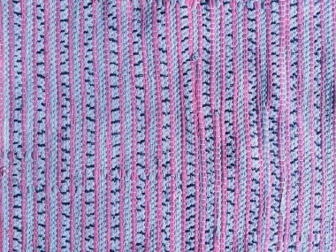El dokuması kumaş bir paspasın, pembe ve mavi tonlarda örülmüş dokusu olan makro fotoğrafı. Tekstil tasarımı veya dijital arkaplanda kullanmak için ideal.