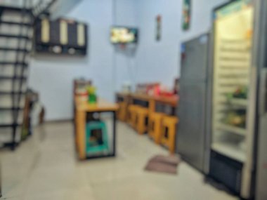 Yemek masaları, buzdolabı, tabure ve merdivenleri olan modern bir restoran içinin bulanık görüntüsü. Arkaplan, model ya da yiyecekle ilgili tasarım için mükemmel.