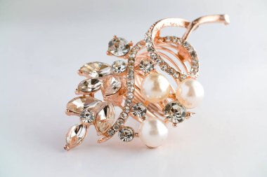 Yapraktan esinlenerek dizayn edilmiş, yuvarlak ve Markiz kesimi saf elmaslı, altın bir gül yüzüğünün yakın çekimi. Ayrıntılı, parlak ve temiz beyaz arka planda zarif..