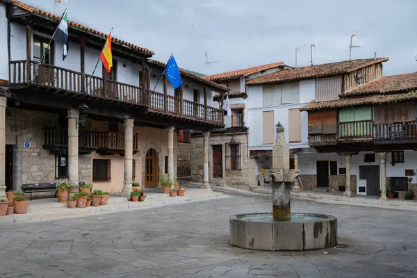 İspanya 'nın Cceres eyaletinde tarihi bir köy olan Valverde de la Vera' nın ana meydanının büyüleyici manzarası. Boş meydanda geleneksel taş binalar, ahşap balkonlar ve La Vera bölgesinin tipik eşsiz mimari tarzı yer alıyor..