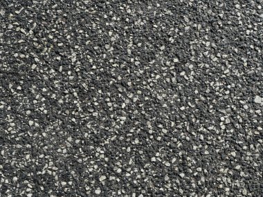 Asfalt yol yüzeyinde beyaz çentikler var. Beyaz çakıllı asfalt yol yüzeyi kavramayı ve güvenliği sağlar. İlginç doku, bir arkaplan ya da yol yapım temaları için ideal.