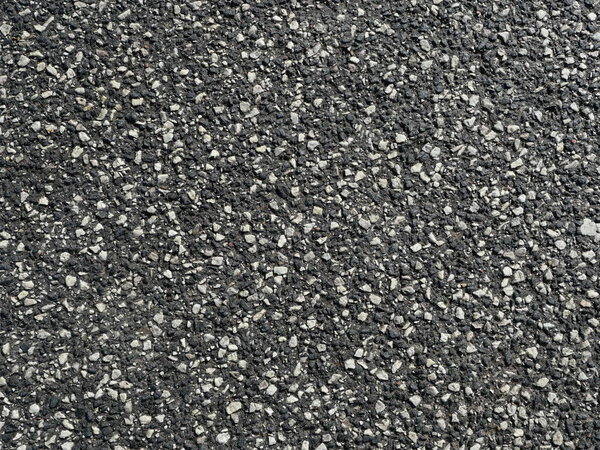 Асфальтовое дорожное покрытие с белой щебнем. Асфальтовая дорожная поверхность с белым гравием обеспечивает сцепление и безопасность. Интересная текстура, идеально подходит в качестве фона или для дорожного строительства.