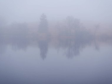 Harz 'da sisli bir maden göleti. Harz 'da gizemli bir maden göleti. Kış mevsiminde sis, yansımalar ve ufuklar muhtelif temalar için mükemmel esrarengiz bir atmosfer yaratır..