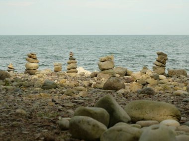 Sahilde taş cairns. Sahilde kule ve figürler oluşturmak için istiflenmiş taşlar, turistlerin denge ve farkındalığın bir işareti olarak üst üste yığdıkları popüler fotoğraf motifleri. Yaratıcı doğanın bir sembolü..