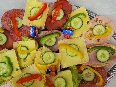 Sandwiches with sausage and cheese, garnished with cucumber and peppers  a popular savory snack for events and parties, perfect for any buffet. Space for text and design. clipart