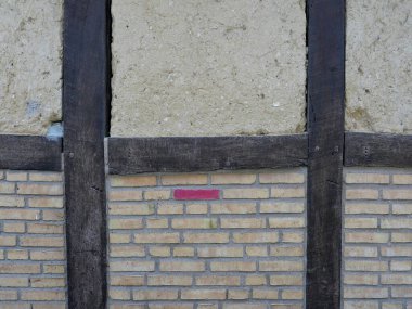 Tuğladan yapılmış yarı ahşap duvarlar, tarihi inşa yöntemlerinin bir parçasıdır ve geçmiş nesillerin işçiliğine tanıklık eder. Metinler ve tasarımlar için boşluk.