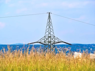 Kentsel alanlardaki yüksek voltajlı kuleler ve hatlar sanayi ve şehirlere enerji sağlıyor. Metinler ve tasarımlar için boşluk.