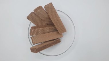 İzole edilmiş beyaz çikolata aromalı gofret çubukları berrak bir cam kasede.  