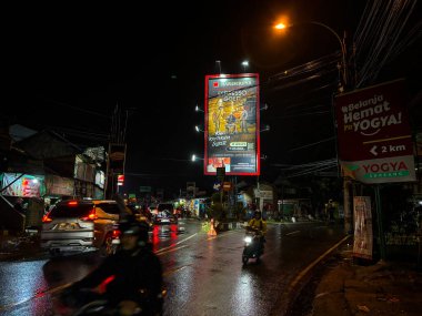 Bandung, Endonezya - Haziran 15, 2025: Gece yarısı bir otoyol kavşağına inşa edilmiş büyük bir reklam panosu sokak ışıklarıyla aydınlatılmış. 