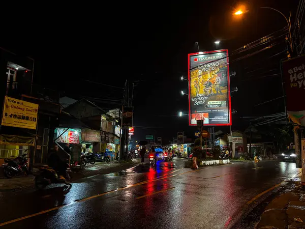 Bandung, Endonezya - Haziran 15, 2025: Gece yarısı bir otoyol kavşağına inşa edilmiş büyük bir reklam panosu sokak ışıklarıyla aydınlatılmış. 