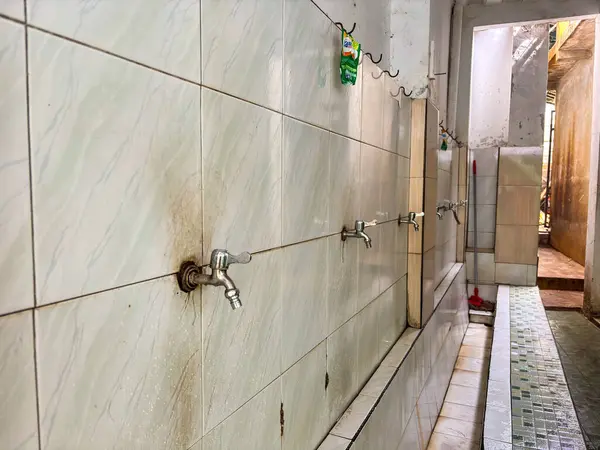 Beyaz seramik bir duvara bir sıra su musluğu monte edildi 