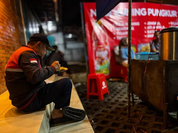 Bando gübresi, Endonezya - 19 Haziran 2025: Otoyol kenarındaki bir yiyecek satıcısından bir kişi akşam yemeğinin tadını çıkarıyor 