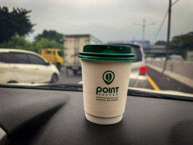 tangerang, indonesia - juni 21, 2025 : Secangkir kopi Point Coffee di dashboard mobil dengan latar belakang jalan raya