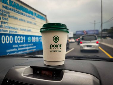 tangerang, indonesia - juni 21, 2025 : Secangkir kopi Point Coffee di dashboard mobil dengan latar belakang jalan raya