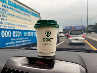 tangerang, indonesia - juni 21, 2025 : Secangkir kopi Point Coffee di dashboard mobil dengan latar belakang jalan raya