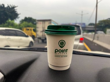 tangerang, indonesia - juni 21, 2025 : Secangkir kopi Point Coffee di dashboard mobil dengan latar belakang jalan raya