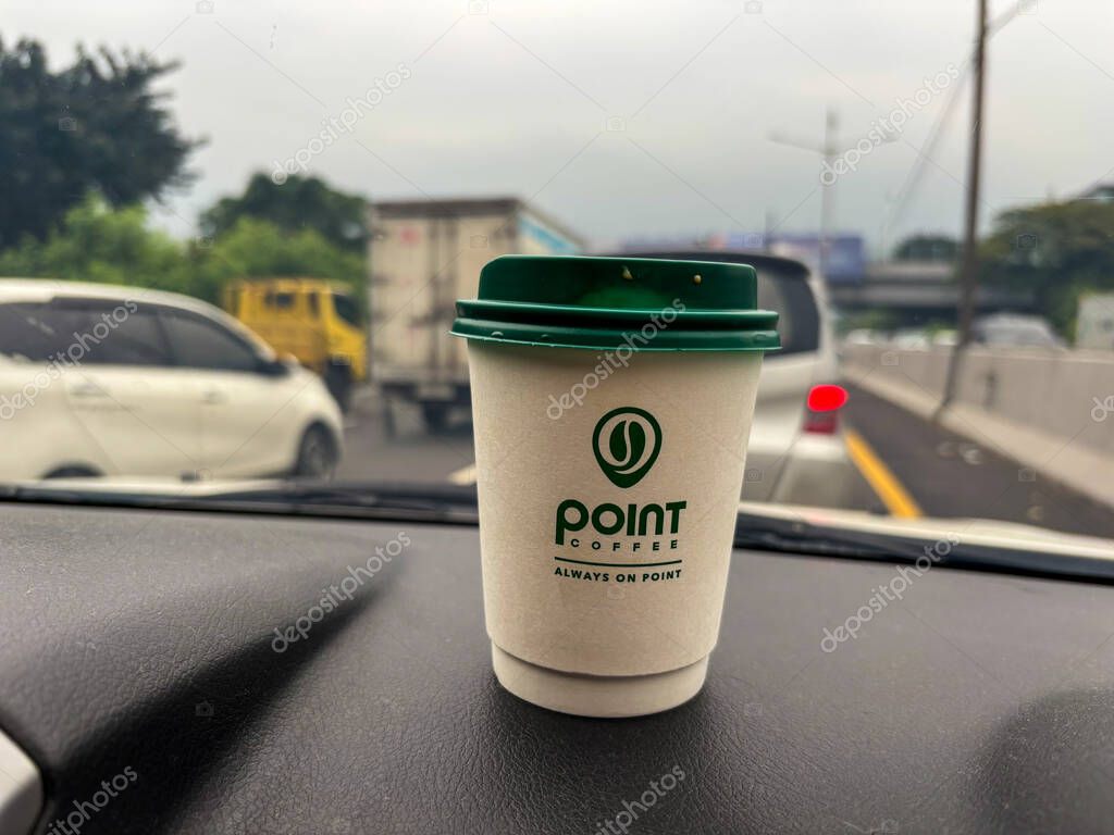 Tangerang, indonesia - juni 21, 2025 : Secangkir kopi Point Coffee di dashboard mobil dengan latar belakang jalan raya