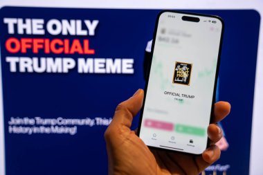 Elinde Moonshot uygulamasında resmi Trump mim logosunu gösteren bir telefon tutan adam, satın alınmaya hazır, arka planda mim 'in grafiğini gösteren bulanık bir monitör var. Budapeşte, Macaristan - 20 Ocak 2025