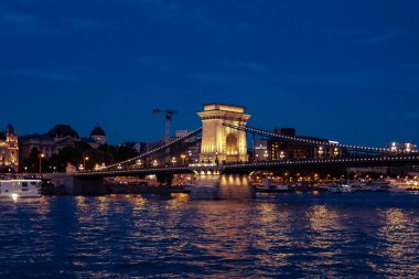 Budapeşte 'de gece. Tuna 'daki Szchenyi Zincir Köprüsü' nün Teknoloji ve Ekonomi Üniversitesi 'ne manzarası. Nehir kenarından gece görüşü. Macaristan, Avrupa.