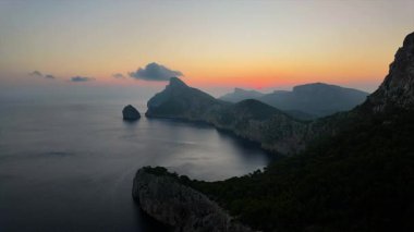 Mirador de Es Colomer 'da gün doğumu, İspanya Formentor, Mallorca' da kayalık uçurumun, denizin ve deniz fenerinin kamera görüntüsü. 4K Zaman Ayarı videosu.