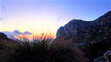 Mirador de Es Colomer 'da Majorcan Vahşi Keçileri, Formentor, Mallorca, İspanya' daki kayalık uçurum, deniz ve deniz fenerinin kamera görüntüsü. 4K video.