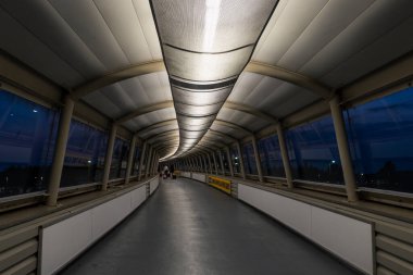 Havaalanı koridorunda (terminal) el çantası ve bavul taşıyan tanınmayan kişiler yürüyor. Dikiz aynası. Glasgow Prestwick Havaalanı, İskoçya, Birleşik Krallık.