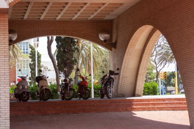 Motorcycles lined up under brick arches. Urban details, transportation, and architectural elements. clipart