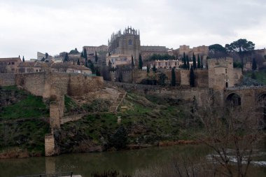Toledo 'lu Alcazar bir tepenin üstünde, şehre ve taş bir köprüye bakıyor. Ortaçağ mimarisi, tarihi eser ve tarih anlayışı..