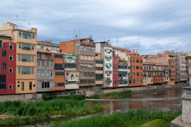 Çeşitli mimari stil ve renklere sahip dar binalar. Avrupa şehri, nehir manzarası ve bulutlu bir gün