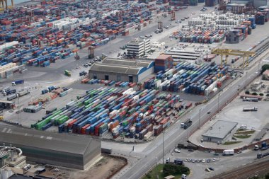  Konteynır deposunda istiflenmiş konteynır ve araçların olduğu sanayi bölgesi. Havadan bakış açısı, lojistik operasyonlar ve belirsiz bir atmosfer.