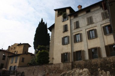 Bergamo 'da açık renkli ve ılık tonlu binaları olan İtalyan mimarisi. Panjurlar ve selvi ağaçları