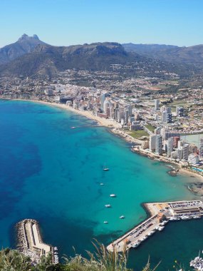 Calpe kıyılarının panoramik manzarası, Costa Blanca, Alicante bölgesi, İspanya. Sahil boyunca gökdelenler, liman, mavi Balear Denizi ve güneşli bir günde dağlar. İspanya 'da tatiller.