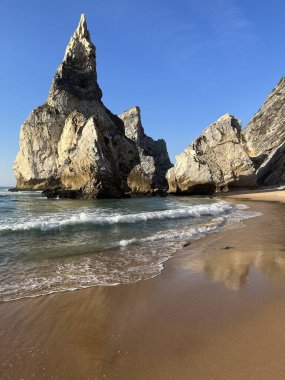 Güneş batarken güneşli bir günde Atlantik Okyanusu 'ndaki kumsal Ursa' da tuhaf üçgen şekilli büyük bir taş. Portekiz 'in simgesi.