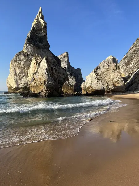 Güneş batarken güneşli bir günde Atlantik Okyanusu 'ndaki kumsal Ursa' da tuhaf üçgen şekilli büyük bir taş. Portekiz 'in simgesi.