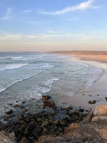 Deniz manzarası: Atlantik Okyanusu 'nda günbatımında güneş tarafından aydınlatılan düz dalgalar ve kumlu sahil şeridi. Praia da Bordeira, Carrapateira.